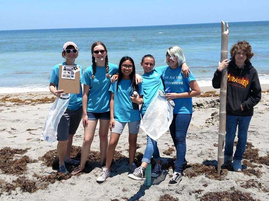 Student cleaning up a beach. (Source: Nature Conservancy).